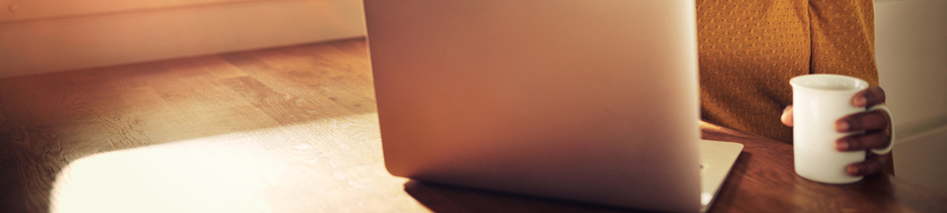 Lady drinking coffee in front of laptop