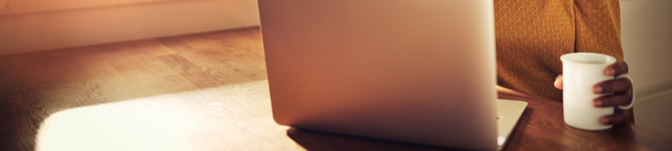 A headless person holding a white mug with a generic laptop open