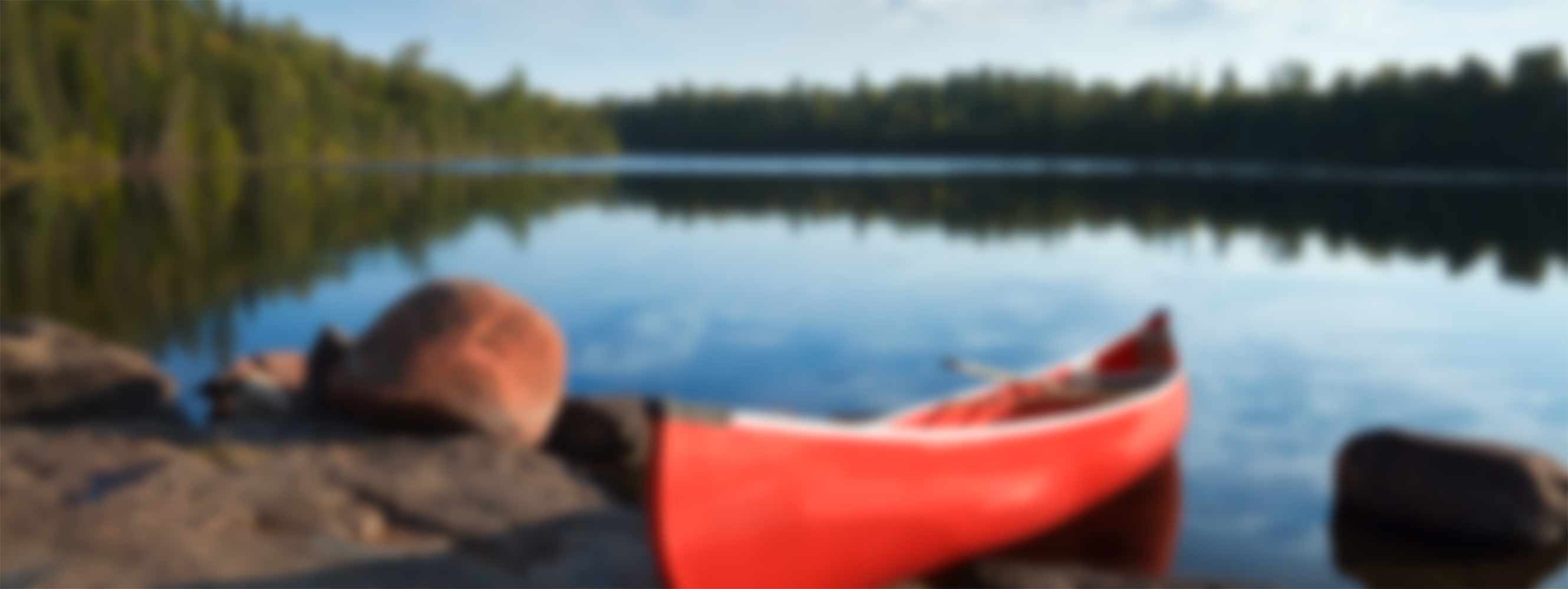 A red canoe parked on the shore of a mountain lake