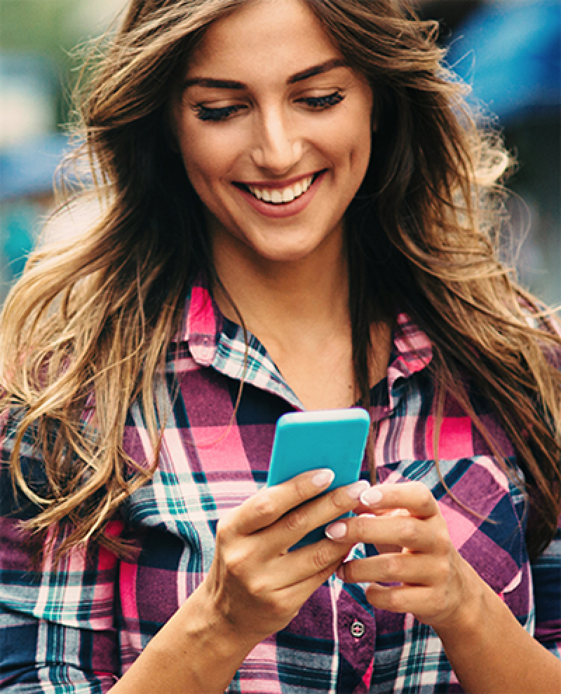 A young woman looking at her smartphone and smiling